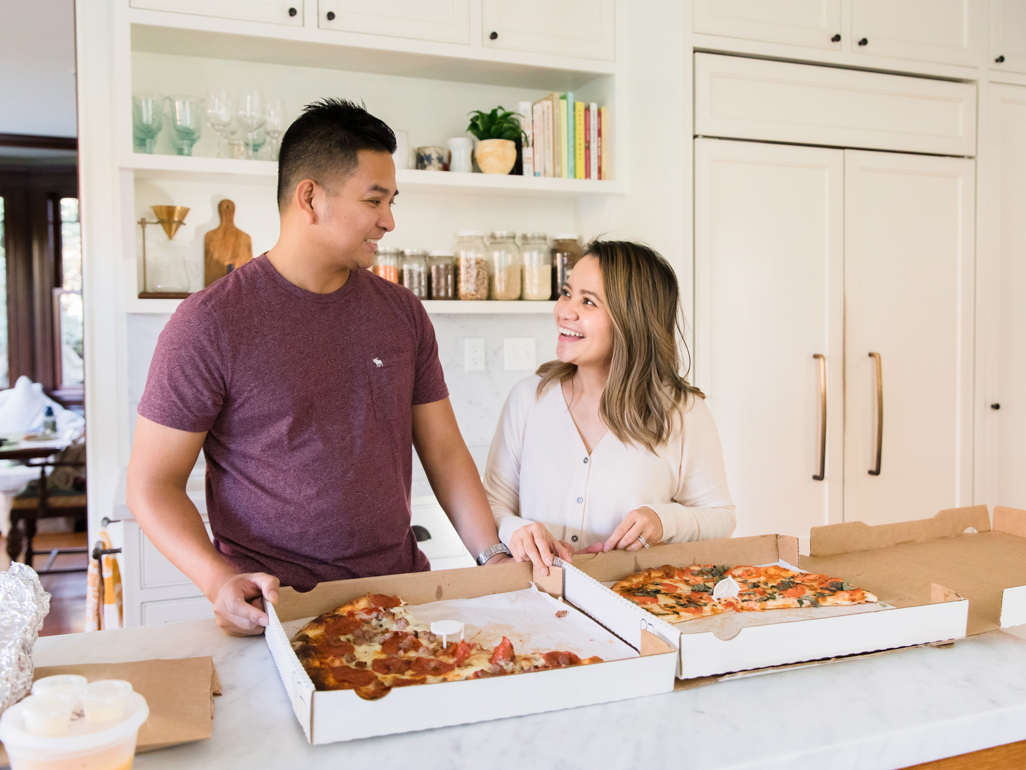 couple standing in the kitchen with a large pizza delivery on the counter