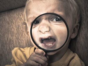 A child holding a magnifying glass over their mouth