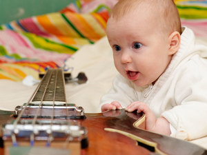 baby eyeing a guitar with curious look on face