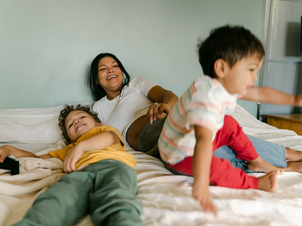 mom with two young sons lounging on bed in bedroom