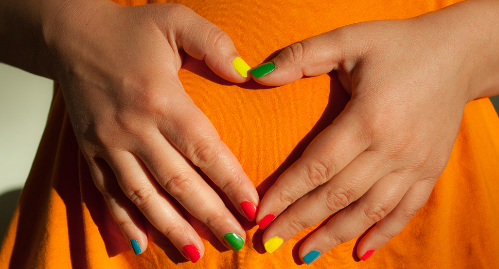 woman wearing colorful nail polish holding her pregnant belly