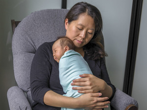 A woman rocking a swaddled newborn