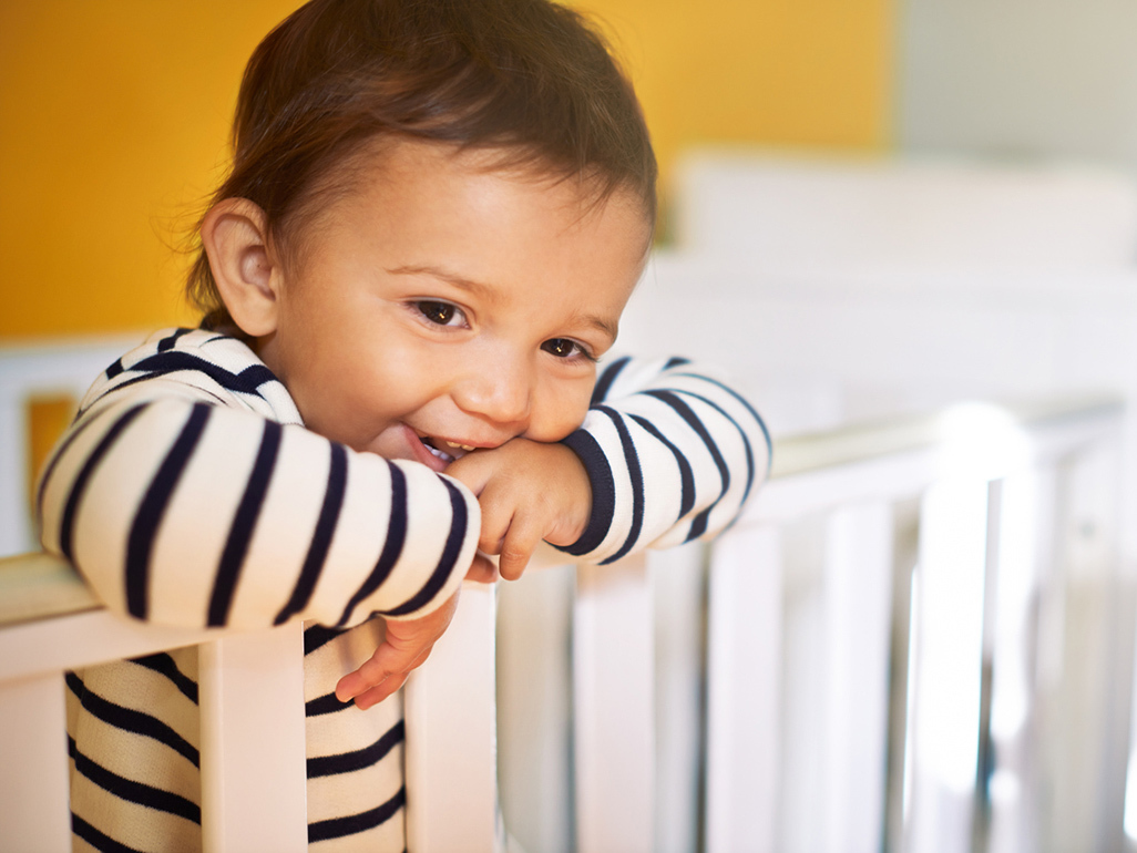 A baby standing in a crib