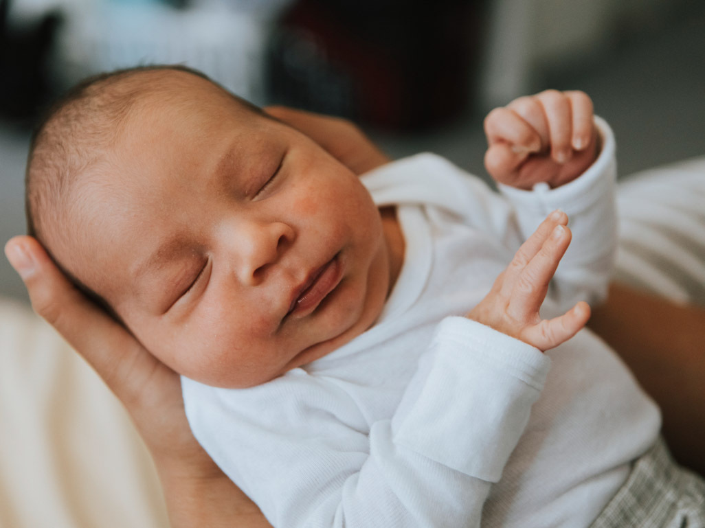 A newborn baby being held in a parents hands, text reads: BabyCenter Answers, Why do babies grunt?