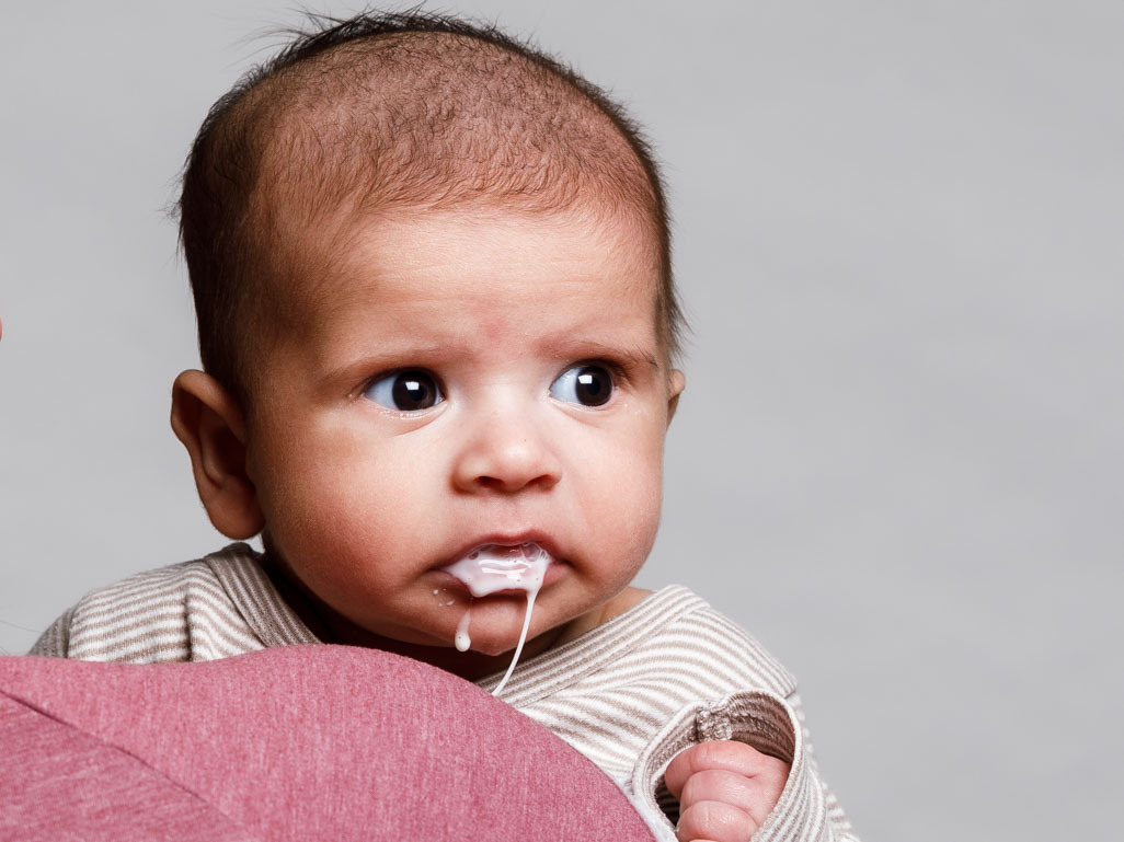 A baby spitting up, the text reads: BabyCenter Answers, Why do babies spit up?