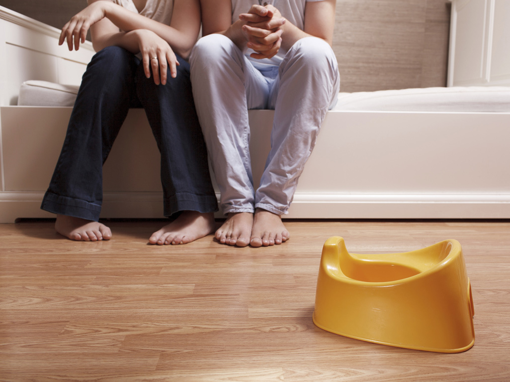 parents sitting on couch with unused potty in front of them