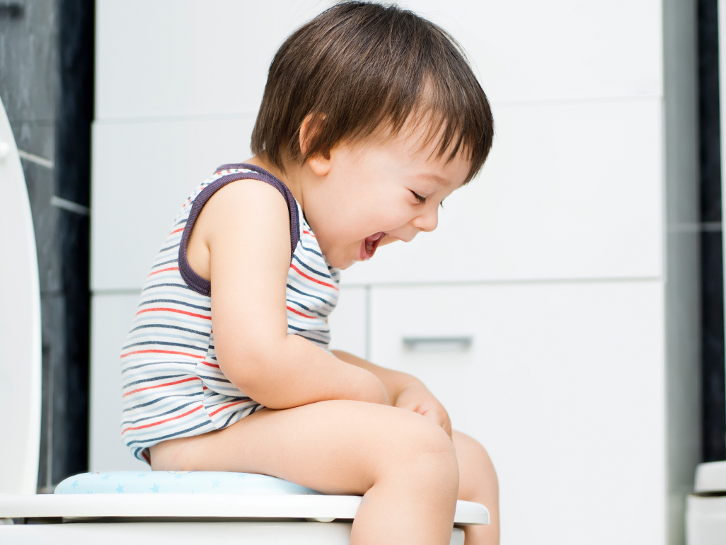 child sitting on a toilet and laughing