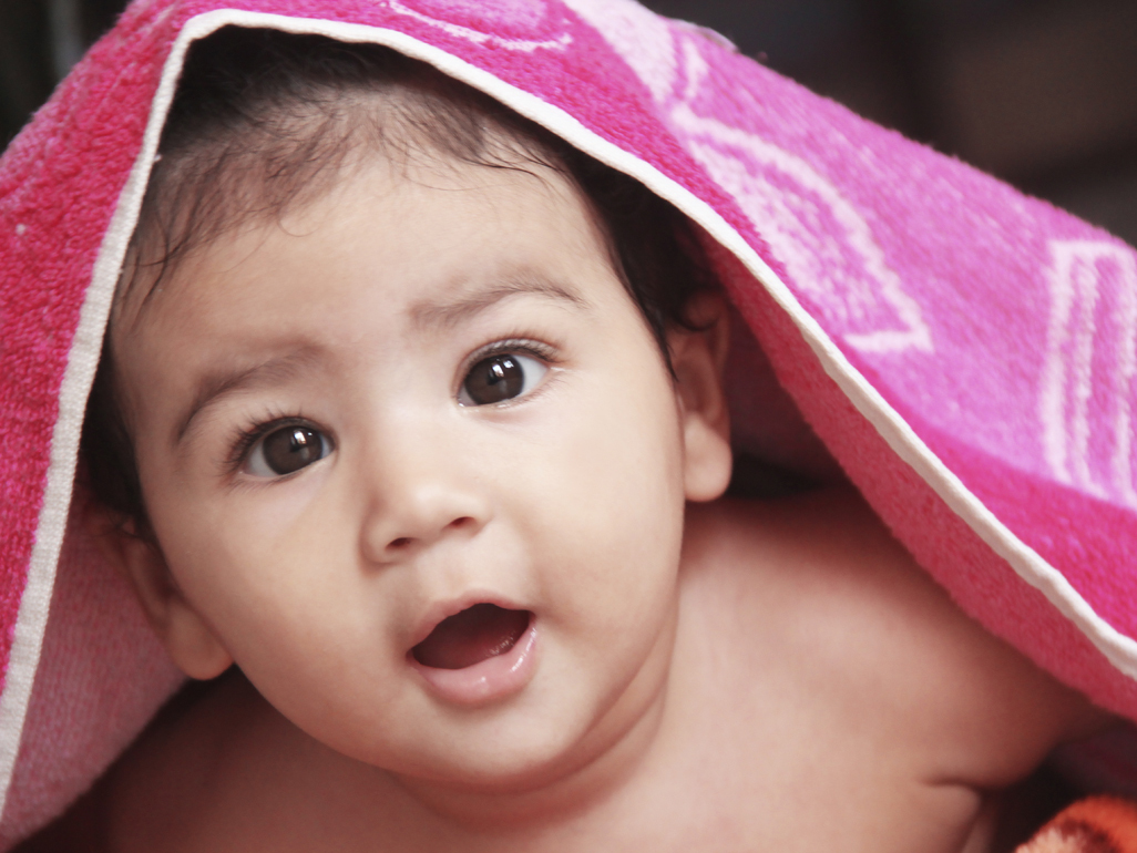 Baby looking from under pink towel