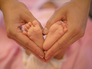 Mum making heart with her hands around her baby's feet