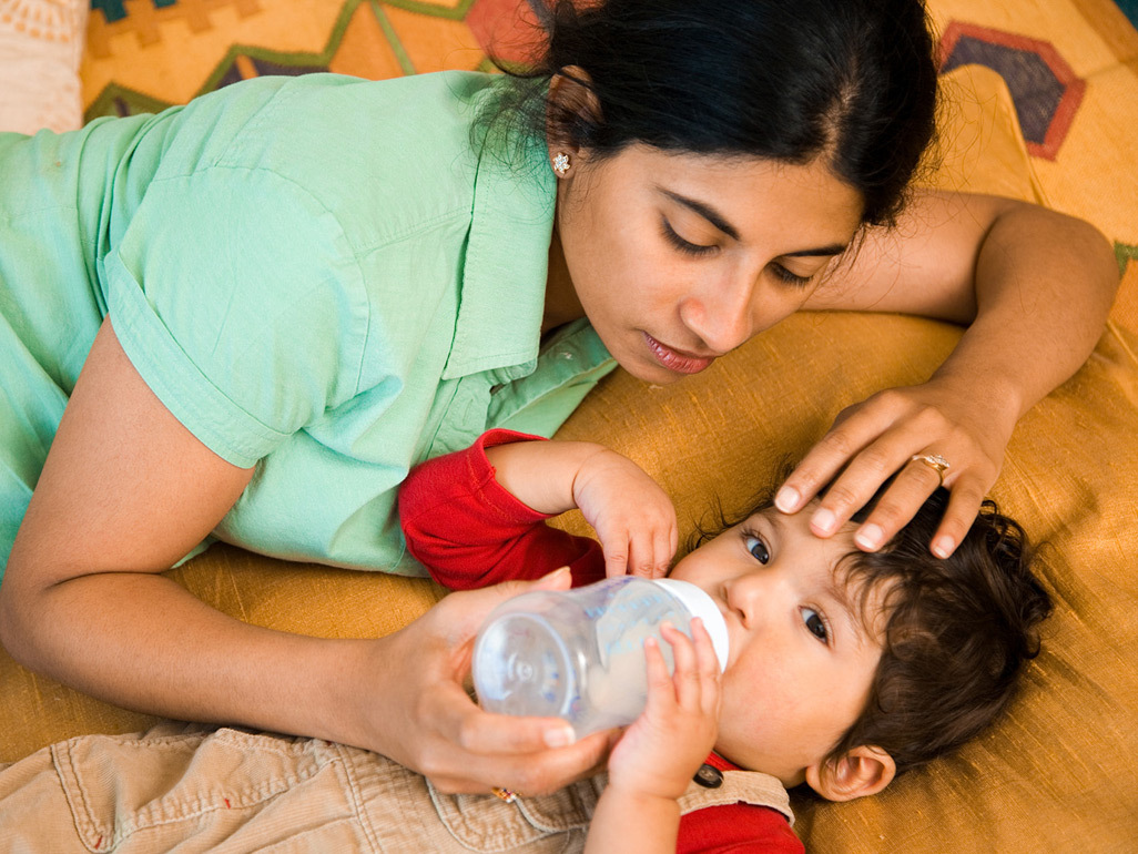 Mother caressing her baby as she gives him formula milk in a bottle