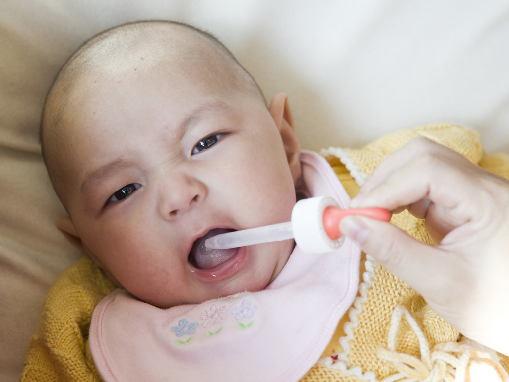 Baby getting medicine from a dropper