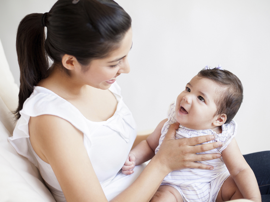 Smiling mum looking at her baby as she holds her up