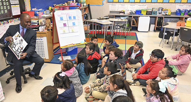 State Superintendent Tony Thurmond reading a book to students in a classroom.