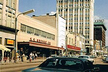 A downtown shopping street. Visible at left-center is a two-story building with modernist design and a sign reading "S. S. Kresge Co."