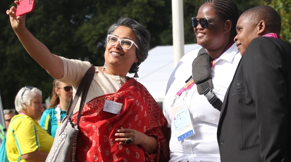 Three people from ethically diverse backgrounds posing and smiling for a selfie photograph to be taken