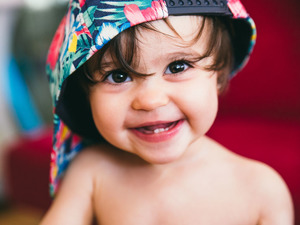 A baby wearing a colorful baseball cap backward