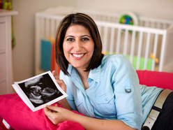 pregnant woman holding photo from her 20-week anomaly ultrasound scan