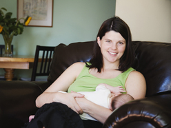 Happy relaxed mum breastfeeding baby on sofa