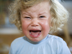 toddler girl having a tantrum and crying, with her face screwed up