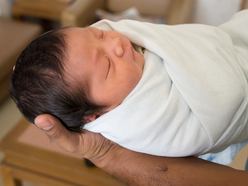 Hand holding swaddled baby