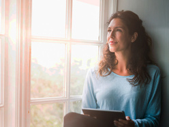 Woman who might be pregnant sitting in a window looking off into the distance