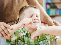 Little boy looking angry and being held back by parent