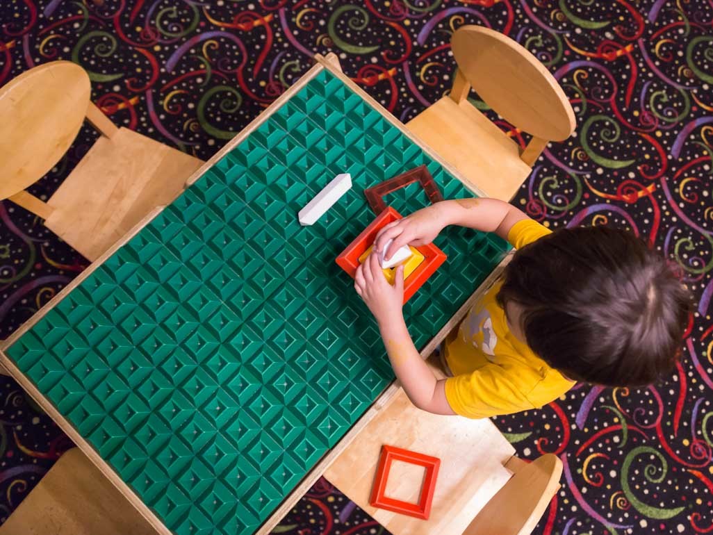 toddler manipulating toy while sitting at table