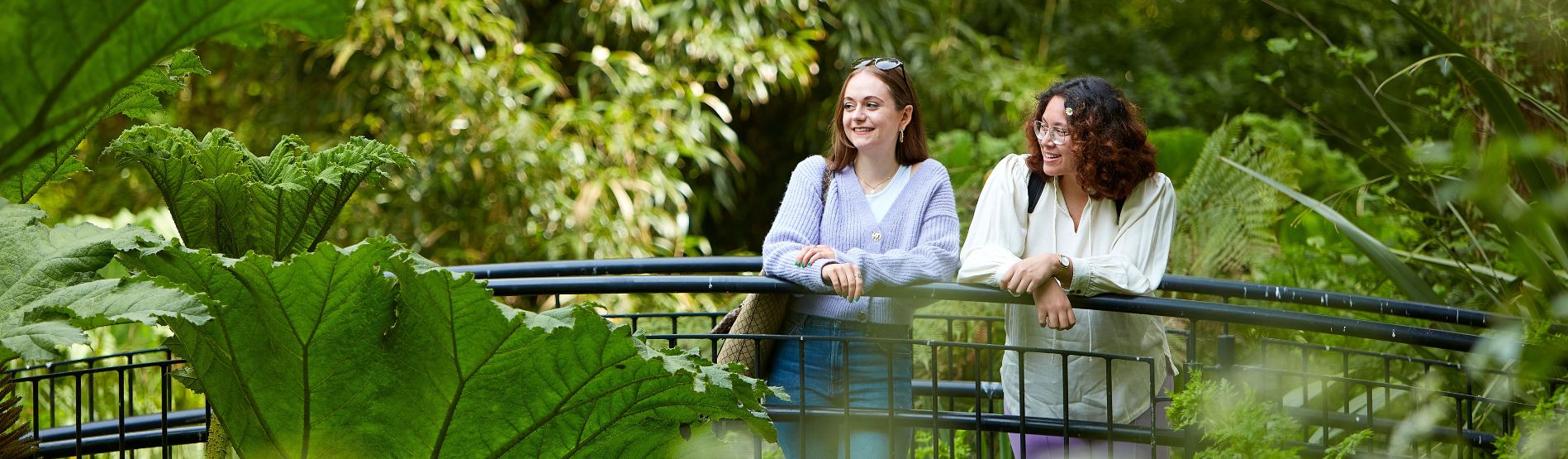 Two smiling students standing on the bridge at Singleton Campus Botanical Garden.