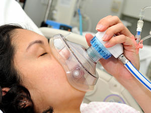 Woman lying in a bed taking gas and air.