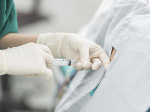 Surgical hands administering an injection into someones back