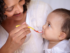 Smiling mum lovingly feeding her baby