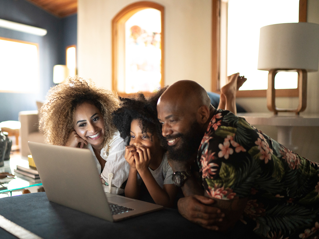 parents and daughter looking at laptop