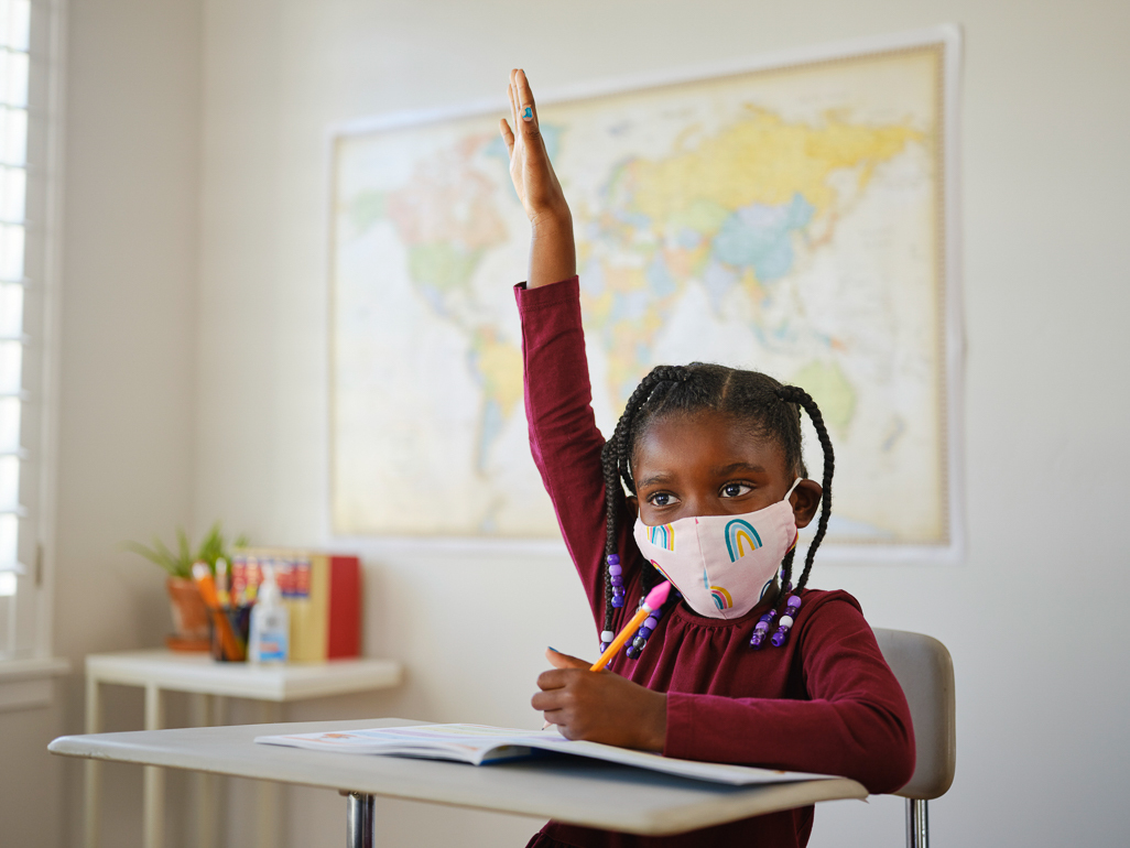 little girl raising her hand in class