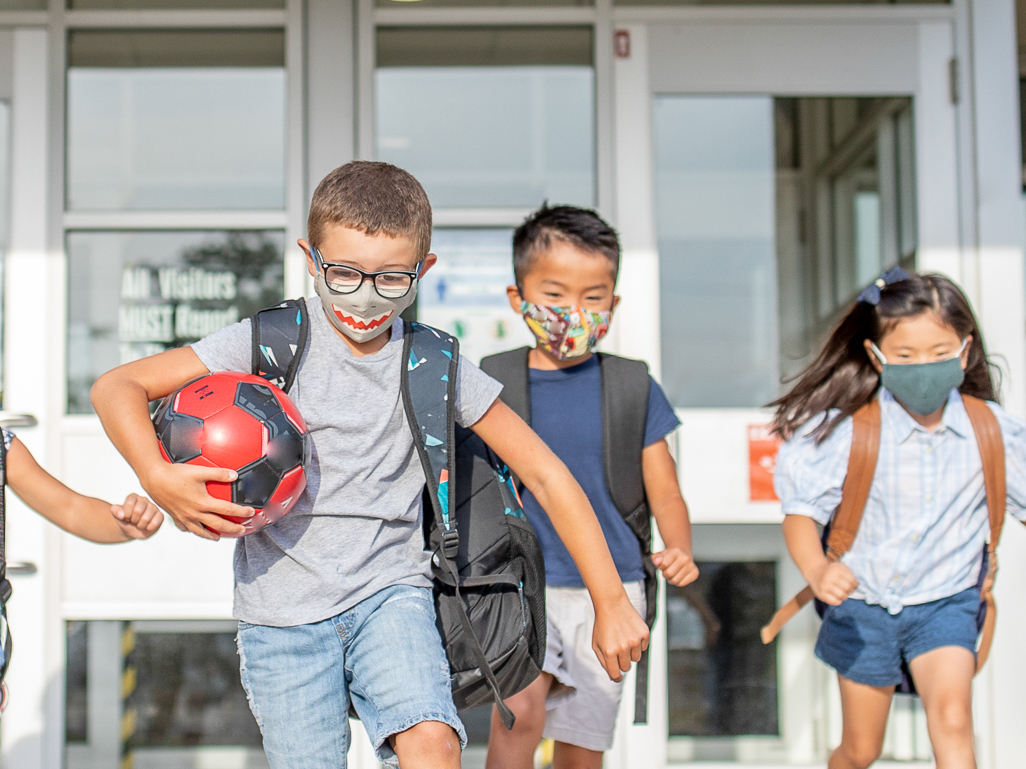 group of kids wearing face masks running back to school