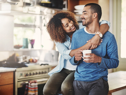 woman hugging mans neck while sitting in kitchen