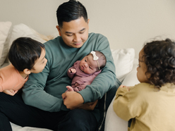 Siblings looking at their newborn sister.