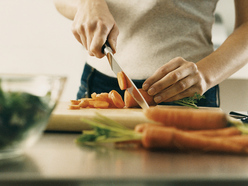 Mujer cortando verduras para cocinar