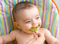 niña comiendo papilla en su silla alta