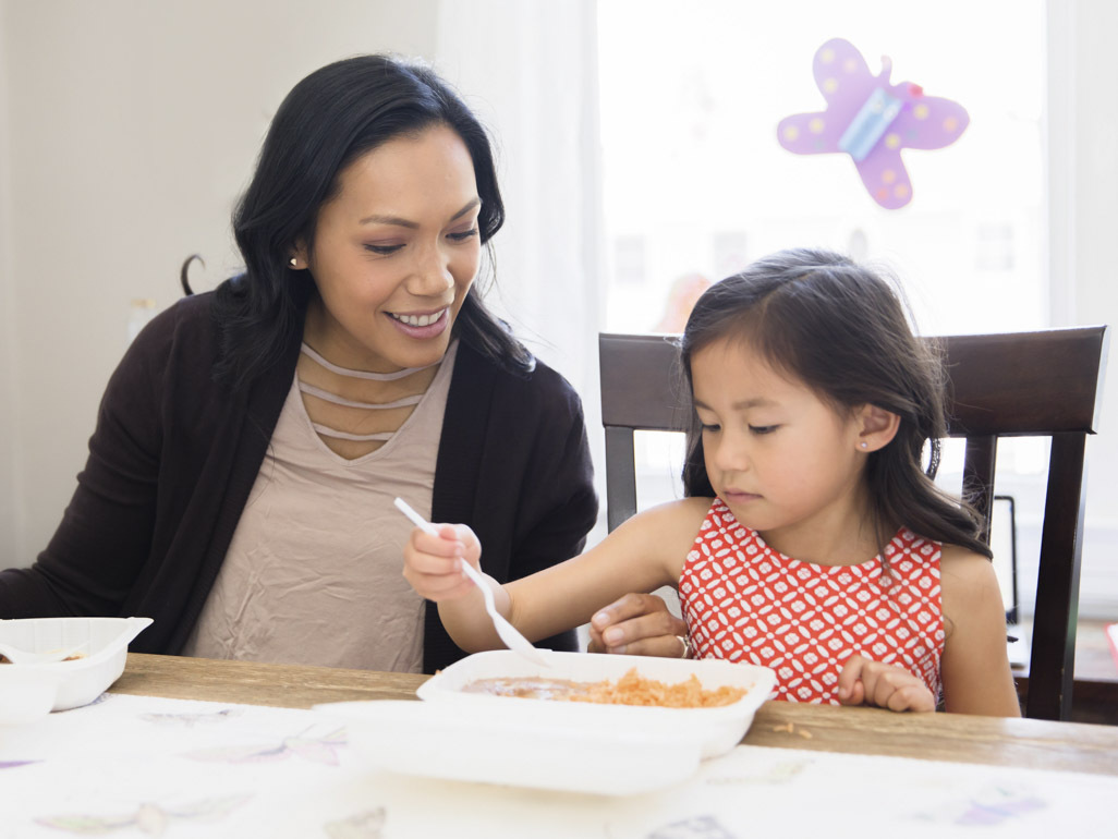 Woman eating at the table with her daughter