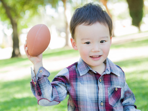 Two year old boy throwing a ball overarm