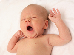 Baby lying down on bed and yawning