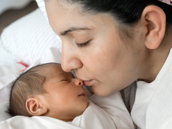 Mother kissing her newborn baby