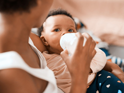 A person feeding a baby a bottle