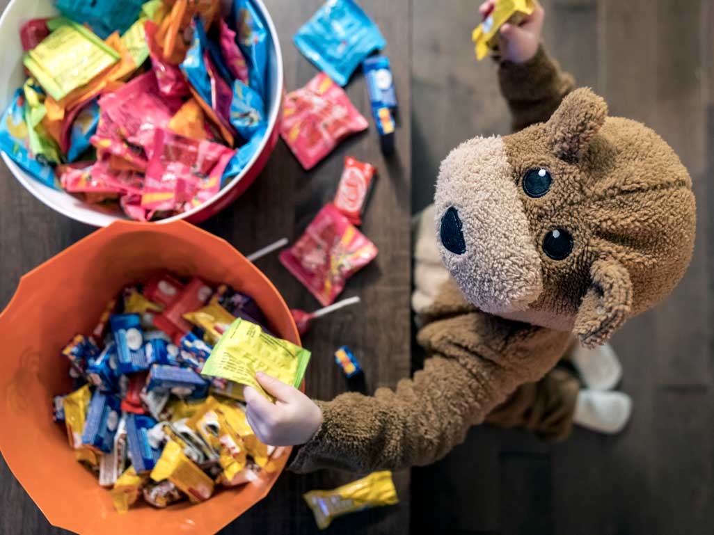 toddler reaching into bucket of Halloween candy