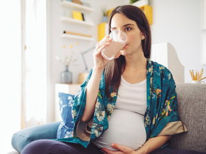 A pregnant woman drinking a shake in a glass