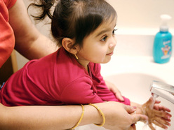 Criança pequena aprendendo a lavar as mãos