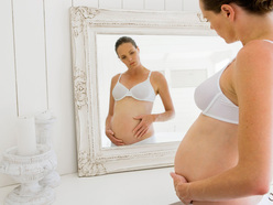 woman looking at her pregnant belly in the mirror