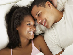 couple in bed smiling at each other