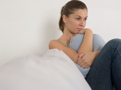 Woman looking worried and holding cushion