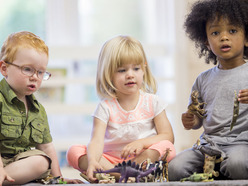 three toddlers sitting together and playing with toy animals